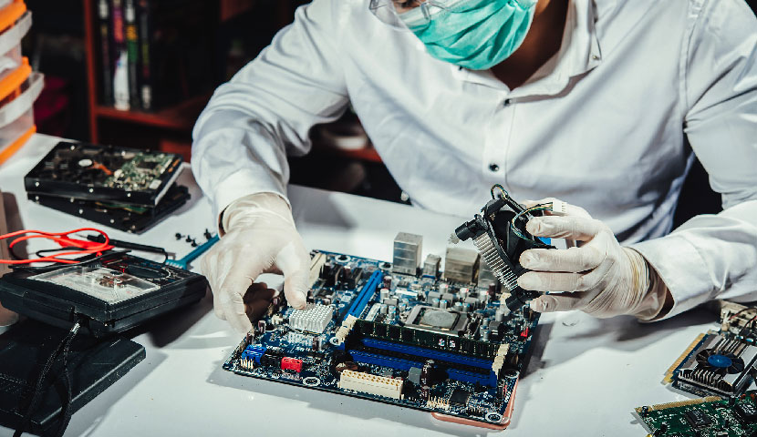 Hombre en laboratorio de RRINTEC armando la tarjeta madrea junto a los componentes de una computadora 